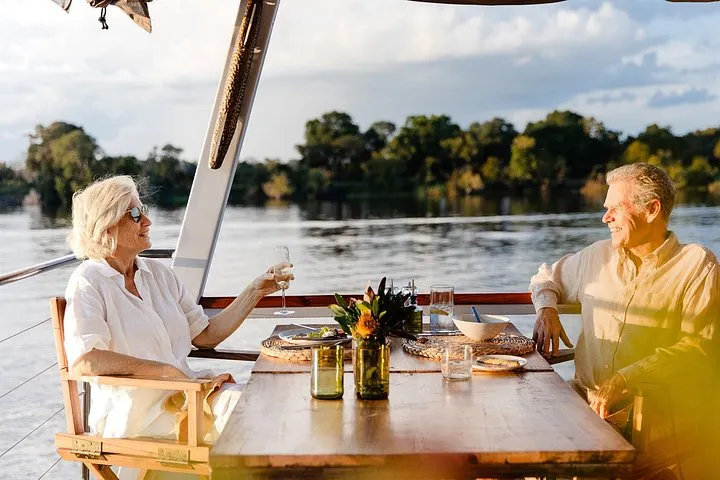 Guests at dinner on deck during a dinner cruise, one of the Zambezi River tours from Victoria Falls