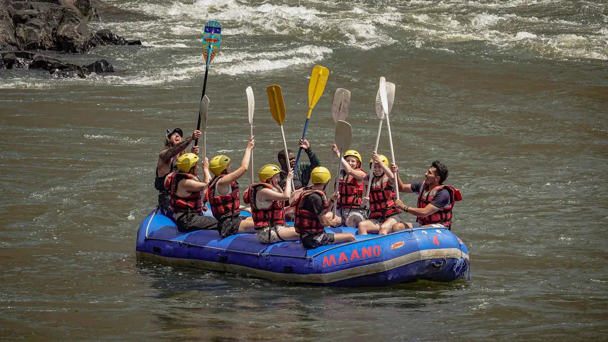 Rafters paddling through a Class 5 rapid on a half day of Zambezi River tours from Livingstone